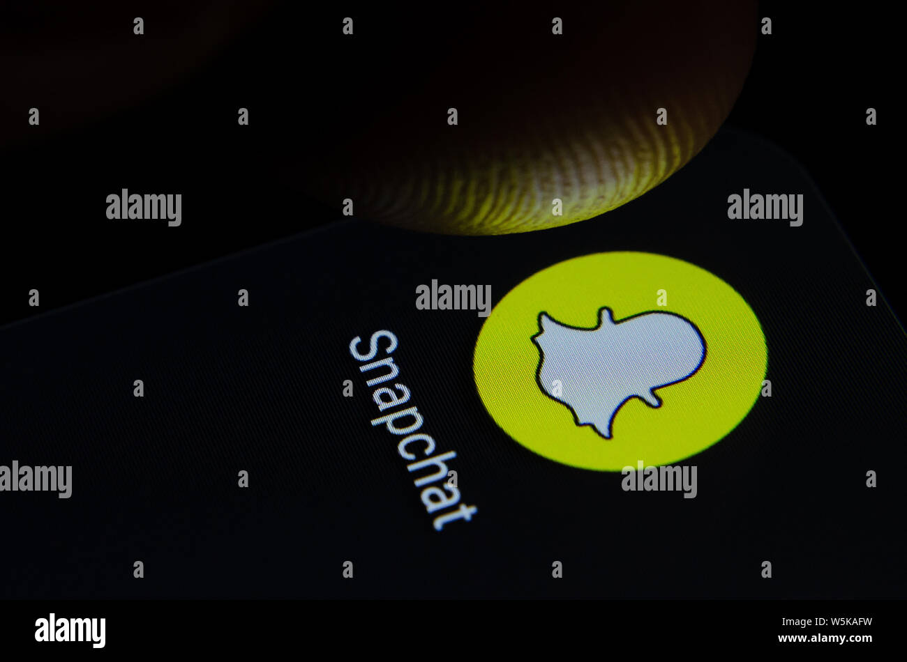Icône de l'application Snapchat sur l'écran du smartphone avec pixels visibles et le doigt sur le point de lancer. Banque D'Images