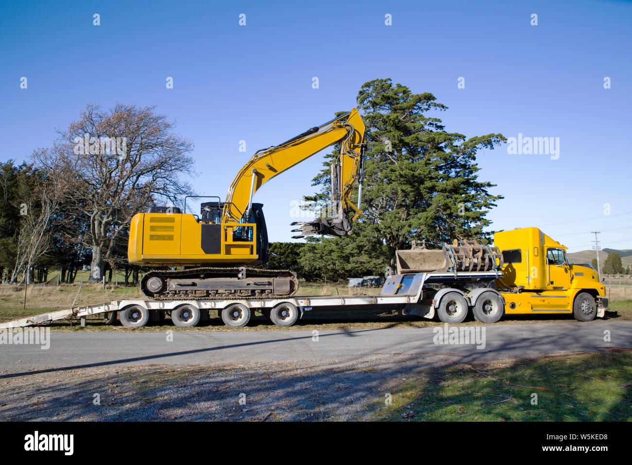 Un grand digger jaune est chargé sur un camion et unité tailer après avoir terminé un emploi à Canterbury, Nouvelle-Zélande Banque D'Images