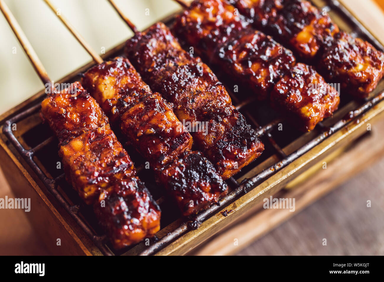 Brochettes grillées traditionnel indonésien de tempe sur charbons chauds close up. La nourriture végane concept. Vue d'en haut. Banque D'Images