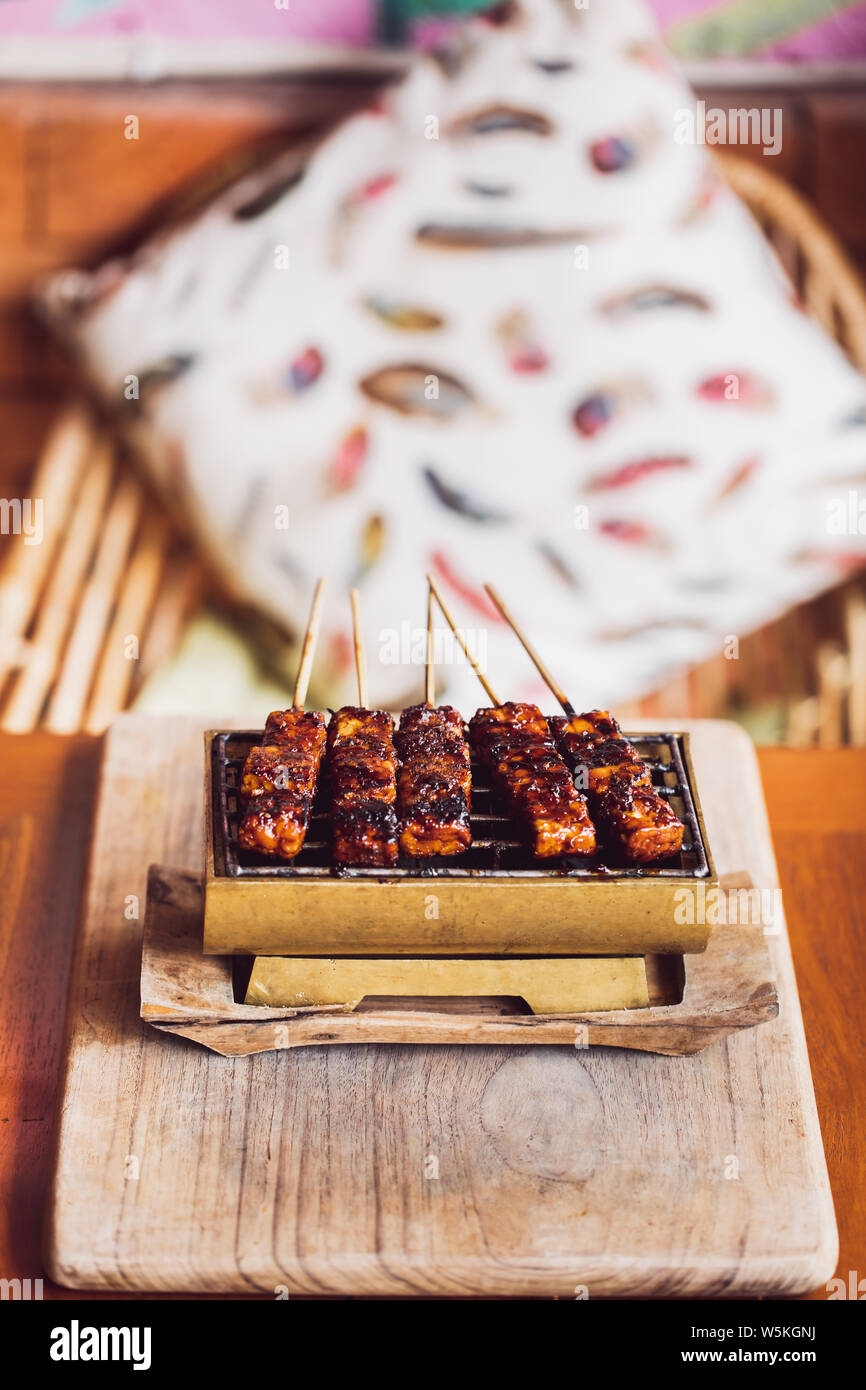 Brochettes grillées traditionnel indonésien de tempe sur charbons chauds close up. La nourriture végane concept. Vue d'en haut. Banque D'Images