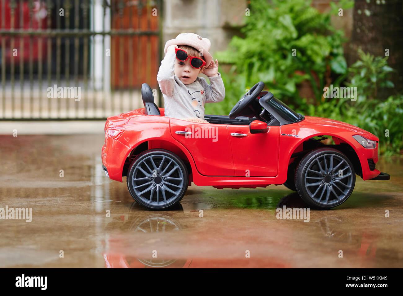 Pretty baby girl in red petite voiture à la à l'appareil photo Banque D'Images