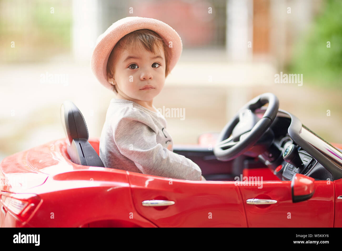 Cute baby girl portrait s'asseoir dans le fond du parc de voiture jouet Banque D'Images