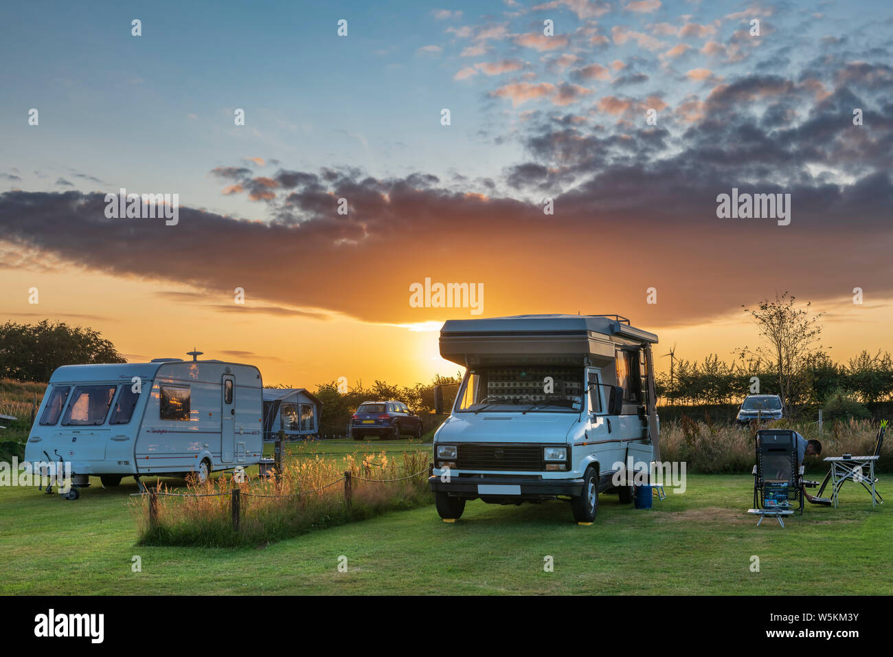 Le soleil se couche derrière un camping-car sur un camping populaire après une belle journée d'été dans le Nord du Devon. Banque D'Images