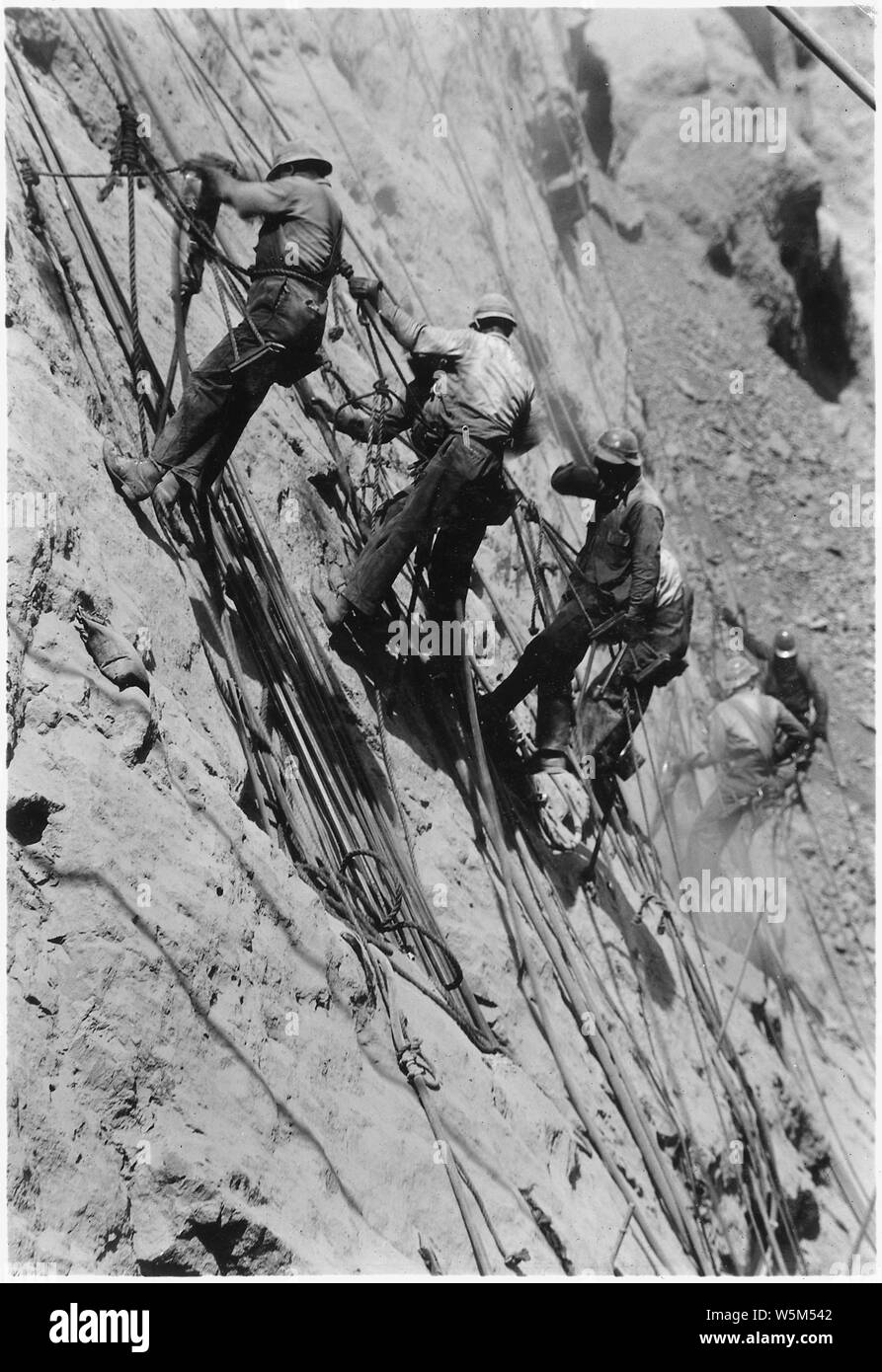 Les foreurs au travail sur le mur au-dessus du canyon d'emplacement. ; Portée et contenu : la photographie de deux volumes d'une série d'albums de photos documentant la construction de barrage Hoover, Boulder City, Nevada. Banque D'Images