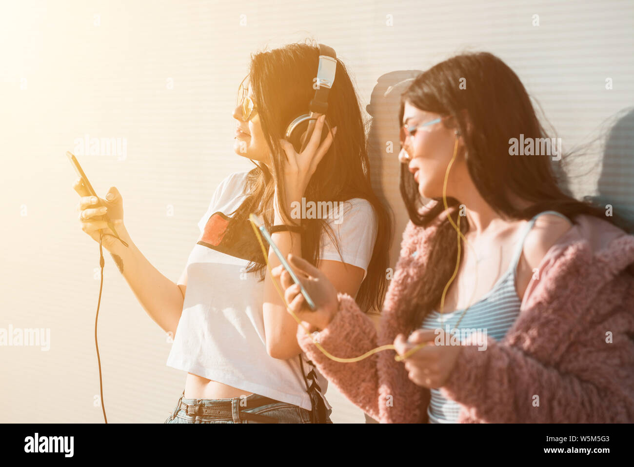 Deux jeunes femmes d'écouter de la musique sur les smartphones Banque D'Images