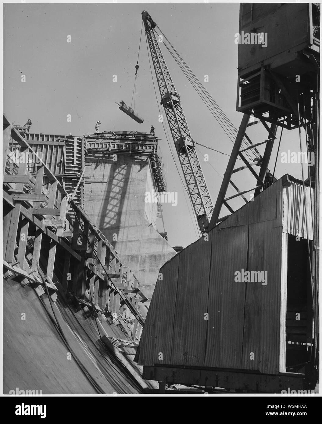 Construction de la section en accolade du déversoir, la jambe raide-employant des derricks avec 110-ft d'élever le matériel et les fournitures pour le haut de la structure. Project Los Angeles River Amélioration. Location Hansen Barrage à Tujunga Fonds dans l'état de fonds réguliers. Travaux poursuivis en vertu du contrat n° W-509-Eng.689. Banque D'Images