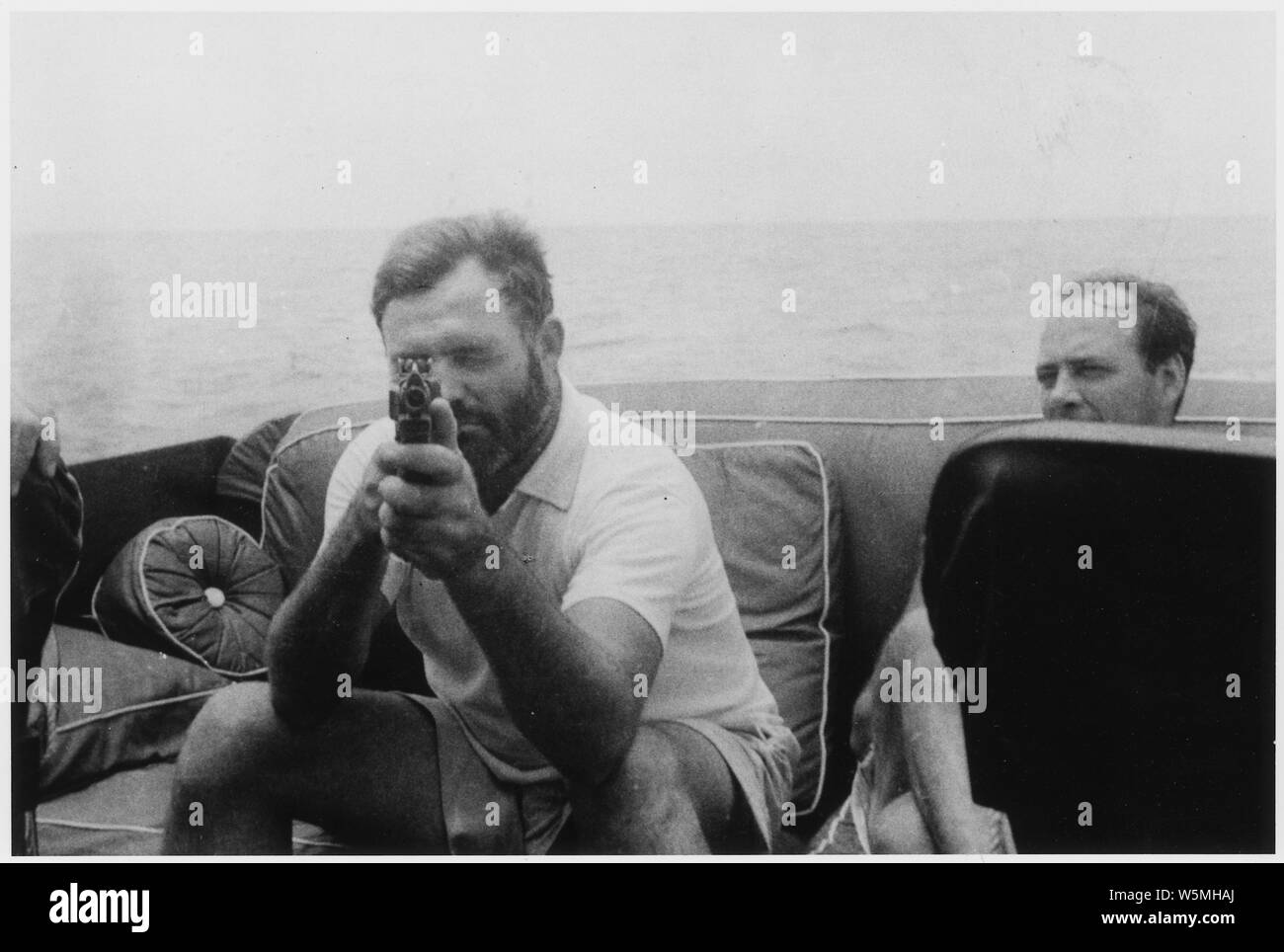 Ernest Hemingway à bord du Pilar 1935 ; Portée et contenu : Photographie d'Ernest Hemingway, tenant un Tommy gun, à bord de son yacht, le Pilar. Banque D'Images