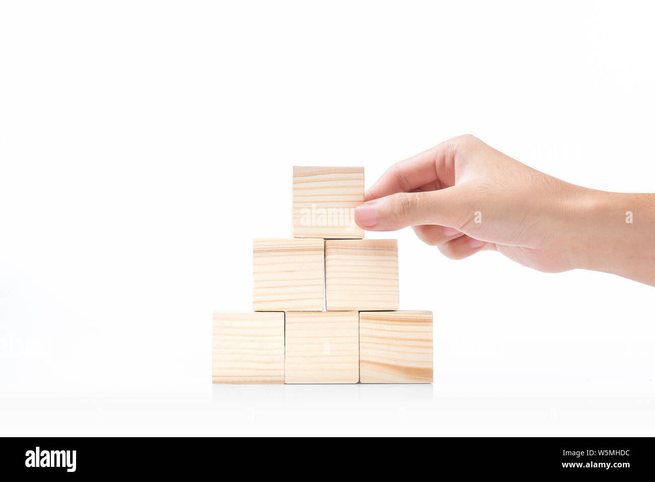 Construire une pyramide de la main d'une cale en bois isolé sur fond blanc Banque D'Images