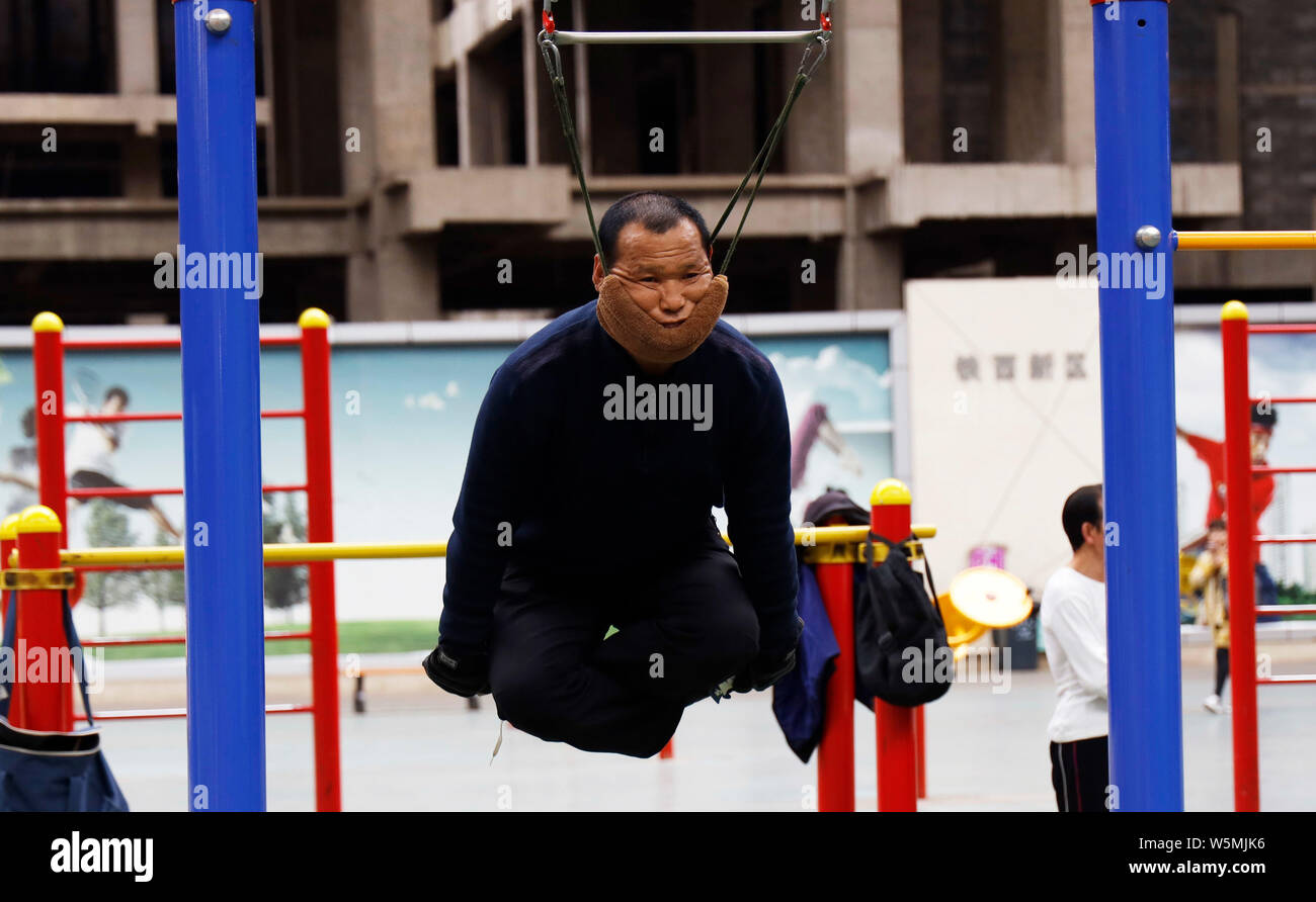 57-year-old Chinese man bien Rongchun exercices avec un engin de traction cervicale périphérique relié à une barre en haut d'un complexe sportif à Shenyang city Banque D'Images