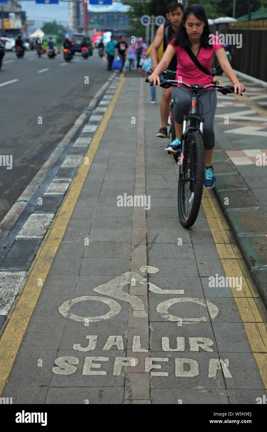 Bogor, Java ouest, Indonésie - Juillet 2019 : une femme et un homme faire de la bycycle sur la bycycle lane. Banque D'Images