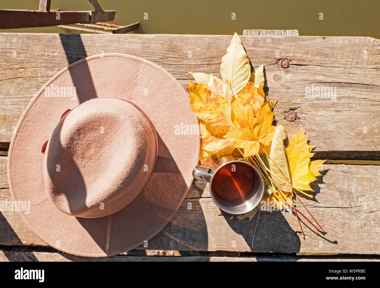 Hat, feuilles jaunes et tasse avec du thé chaud debout sur la jetée en bois près du lac. Week-end à l'automne la nature concept Banque D'Images