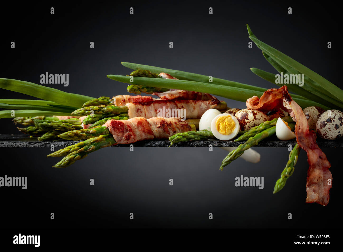 Asperges au bacon. L'asperge verte enrobé de bacon avec des oeufs de cailles et l'oignon vert. Copier l'espace. Banque D'Images