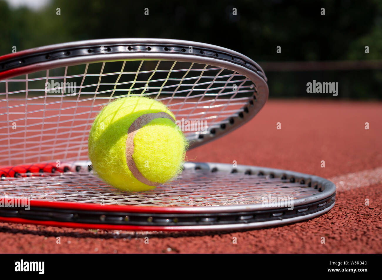 Balle de tennis reposant sur une raquette de tennis sur un disque rouge court, low angle view selective focus Banque D'Images