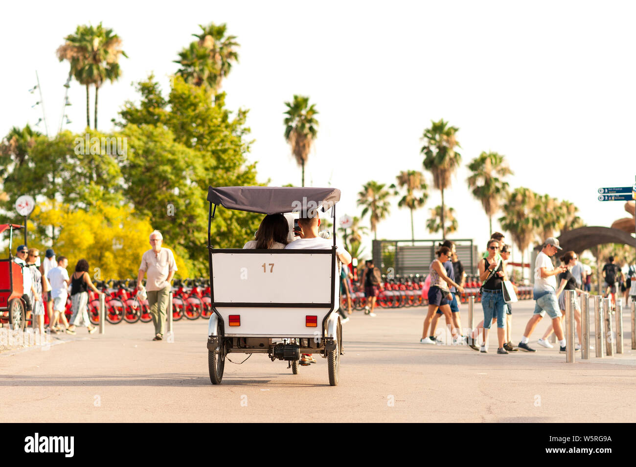 Barcelone, Espagne - 7 juillet 2019 : les touristes en rickshaw vélo au coucher du soleil dans le vieux port de la ville avec des tas de gens. Le tourisme de masse est en train de devenir un problème dans Banque D'Images