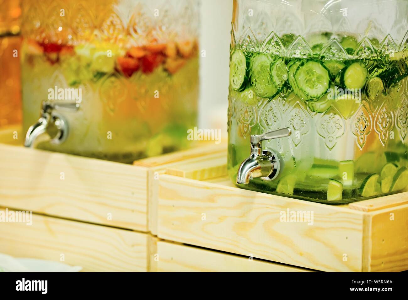Détail sur les fruits et légumes, des boissons dans les distributeurs de boissons grand verre à eau d'une pièce, avec des concombres, des fraises et des limes en verre avec réservoir Banque D'Images