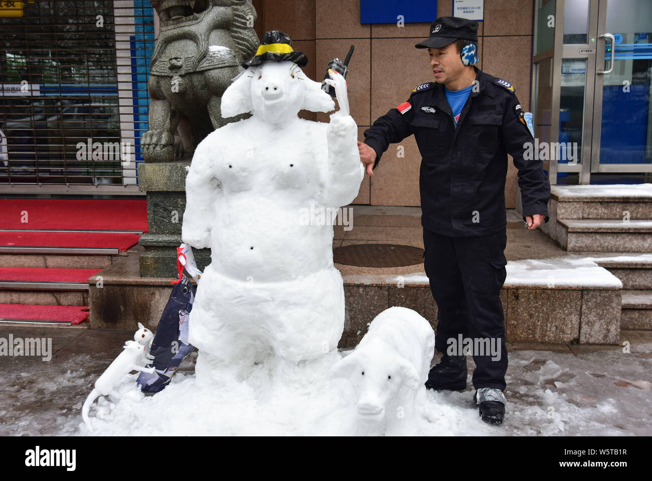 Garde de sécurité de la banque chinoise surnommée Du pose pour des photos avec une sculpture de neige avec la forme de Zhu Bajie, d'un caractère de la classique chinois Banque D'Images