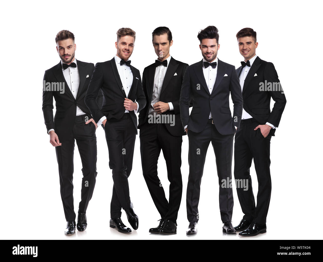 Cinq beaux hommes en noir tuxedoes debout ensemble sur fond blanc, un corps entier photo Banque D'Images