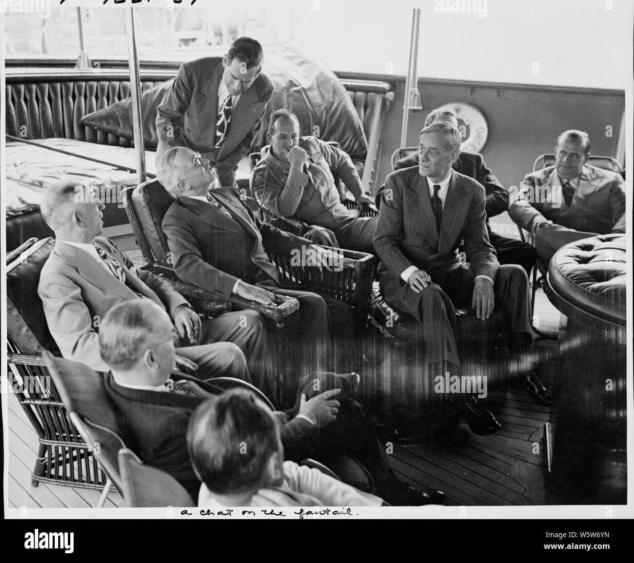 Photographie du Président Truman sur la plage arrière de son yacht, le U.S.S. WILLIAMSBURG, à discuter avec les membres de son parti au premier jour de ses vacances de croisière Bermudes : (assis, de gauche à droite) Homme non identifié ; le secrétaire au Trésor, John Snyder ; Theodore Marks, un ami du Président ; le président ; le général Harry Vaughan, l'aide militaire au Président ; Secrétaire de presse Charles Ross ; Clark Clifford, Conseiller spécial du Président (surtout dans l'ombre) ; George Allen, directeur de la Reconstruction Finance Corporation ; Portée et contenu : la légende originale : (du côté gauche de la fic Banque D'Images
