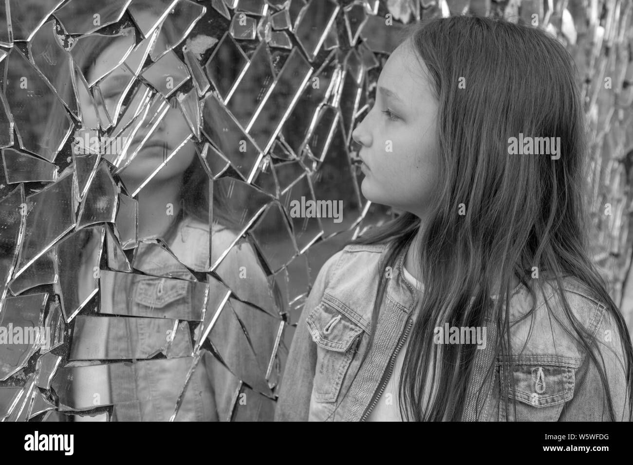 Jeune fille lycéenne l'air triste dans le miroir brisé. Photo en noir et blanc. Banque D'Images