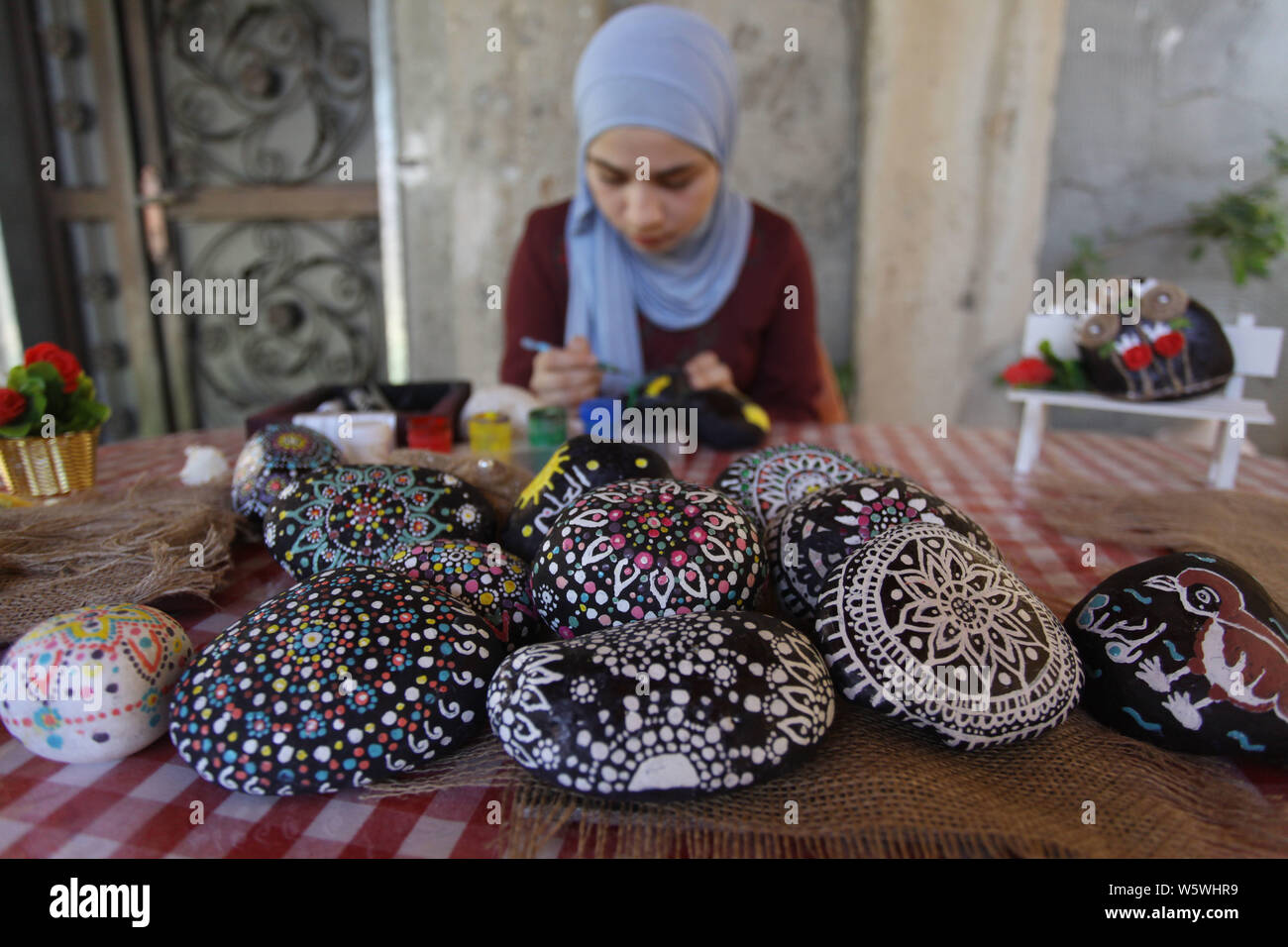 (190730) -- SALFIT, 30 juillet 2019 (Xinhua) -- palestinienne de Marwa Saleh peint sur une pierre à sa maison dans la ville cisjordanienne de Salfit, 30 juillet 2019. Saleh, 16 ans, ramasse des pierres plates et lisses qui permet de tirer d'une rivière près de sa maison. Elle espère avoir une exposition pour afficher ses œuvres artistiques de la peinture de pierre à apporter un certain revenu. (Photo par Nidal Eshtayeh/Xinhua) Banque D'Images