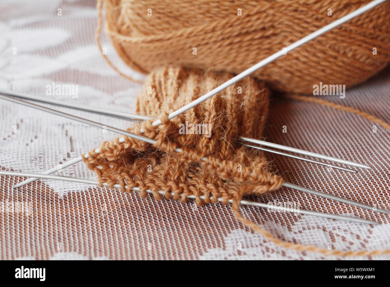 Pelote fil et des aiguilles à tricoter. Tricotez. L'aiguille. Laine à tricoter orteil tricot. Le travail a commencé. Couleur marron. Tricoter des mitaines chaudes avec des aiguilles. Banque D'Images