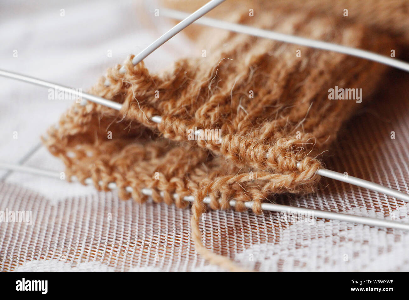 Pelote fil et des aiguilles à tricoter. Tricotez. L'aiguille. Laine à tricoter orteil tricot. Le travail a commencé. Couleur marron. Tricoter des mitaines chaudes avec des aiguilles. Banque D'Images