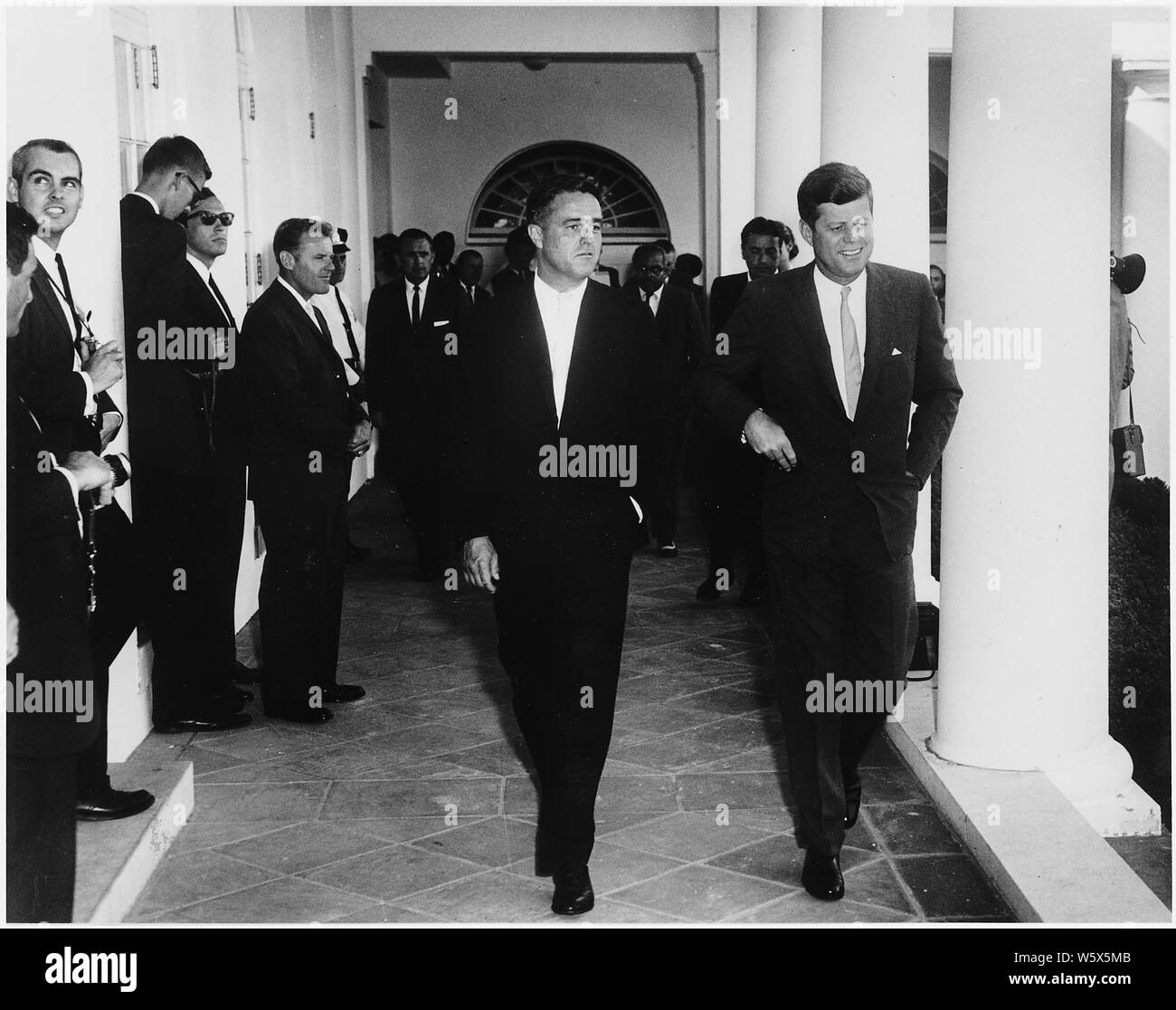 Le président Kennedy salue des volontaires du Corps de la paix au Ghana et Tanganyika. Le président Kennedy, directeur de corps de la paix R. Sargent Shriver, autres. Maison Blanche, colonnade de l'Aile Ouest. Banque D'Images