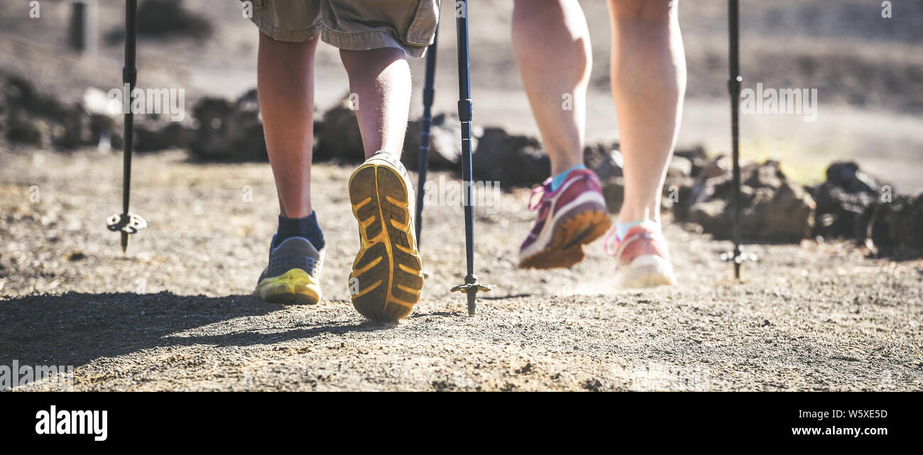 Close up vue panoramique de mère et fils pieds marcher sur un chemin de montagne avec des chaussures de randonnée et des bâtons de marche d'un point de vue de grenouille couple avec quelques s Banque D'Images