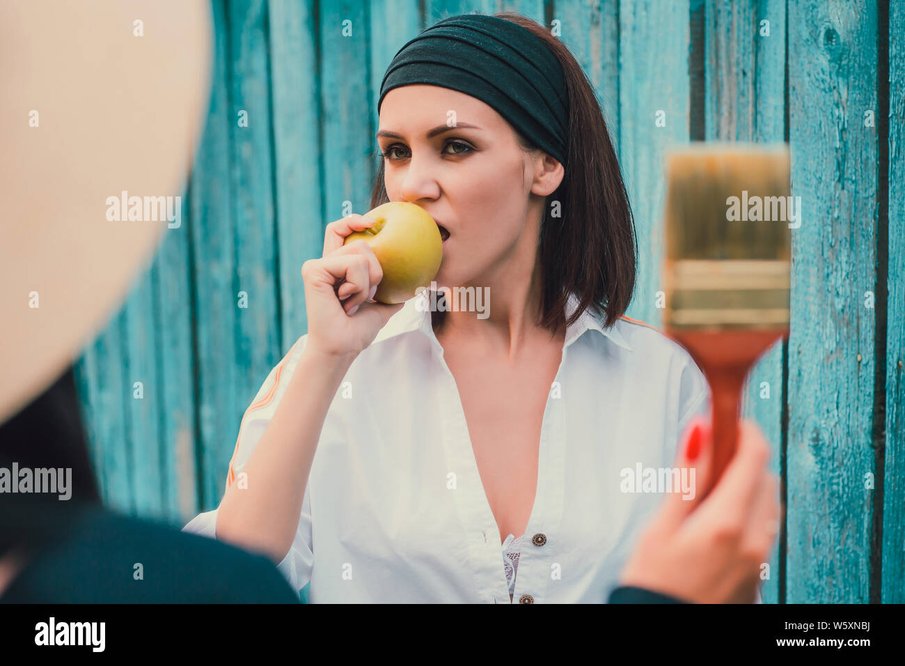 Tom Sawyer jolie femme dans le faisceau de la hat standing en face de clôture. La femme a peint une clôture en bois. Banque D'Images