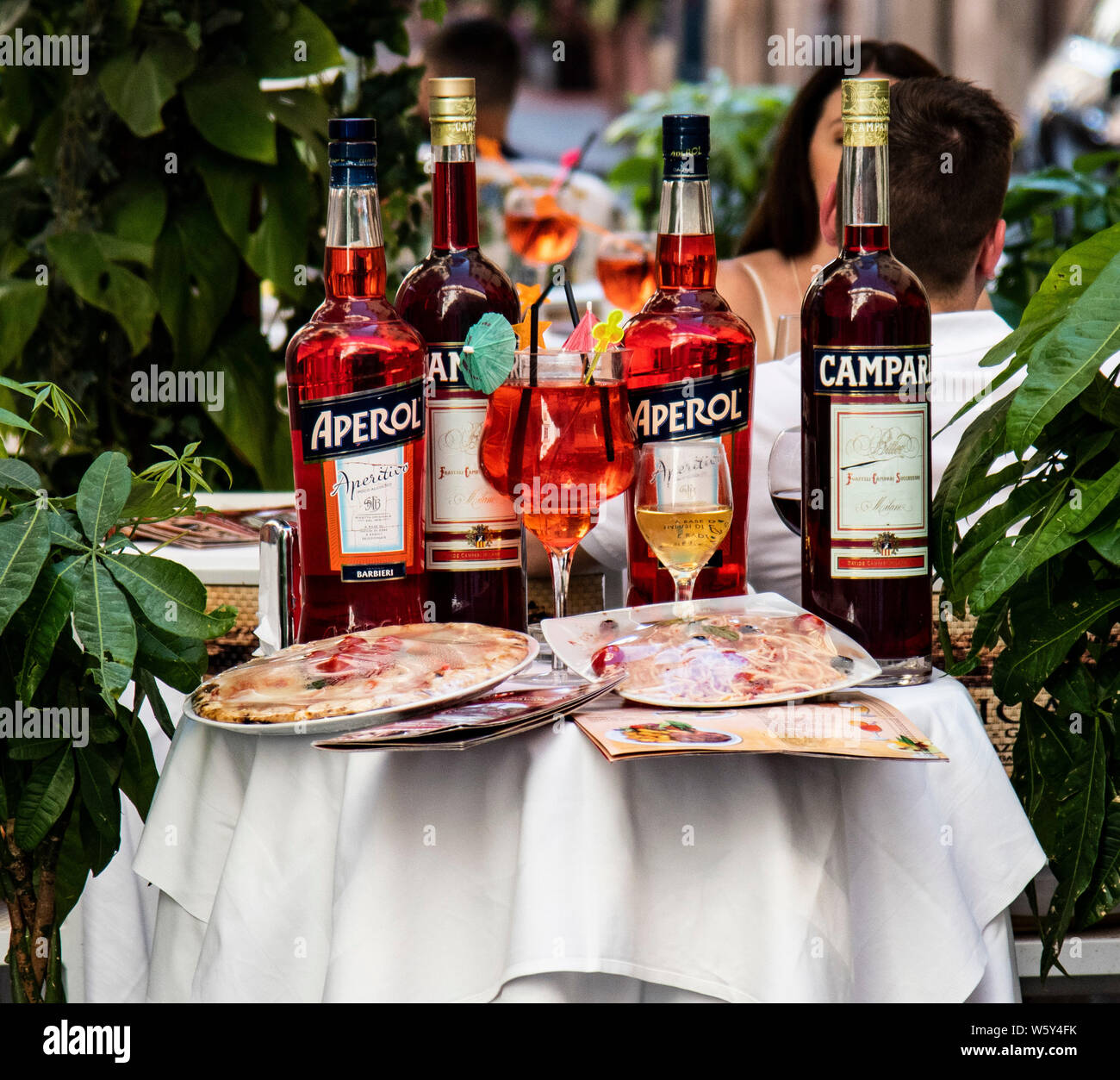 Bouteilles de Campri et d'Aperol sur une table le long des pizzas et menus à l'extérieur d'un café à Rome, Italie Banque D'Images