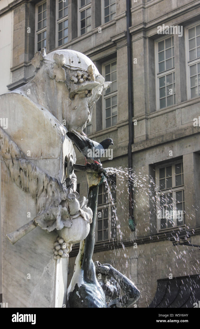 Thursty potable oiseaux historique de fontaine. Les pigeons posés sur Brunnenbuberl Fontaine, Munich, zone piétonne. Banque D'Images