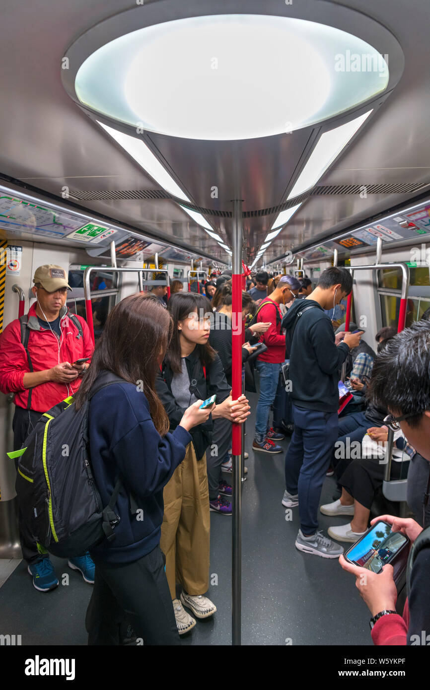 Les passagers d'un train de métro MTR, tous leurs smartphones, Hong Kong, Chine Banque D'Images