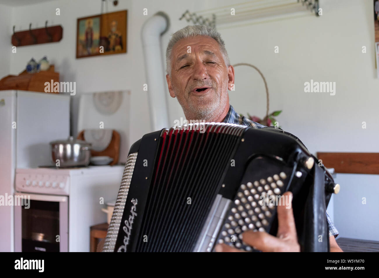 Serbie, 20 juillet 2019 : Portrait d'un homme à l'harmonica et le chant à son domicile dans le village de Solotuša Banque D'Images