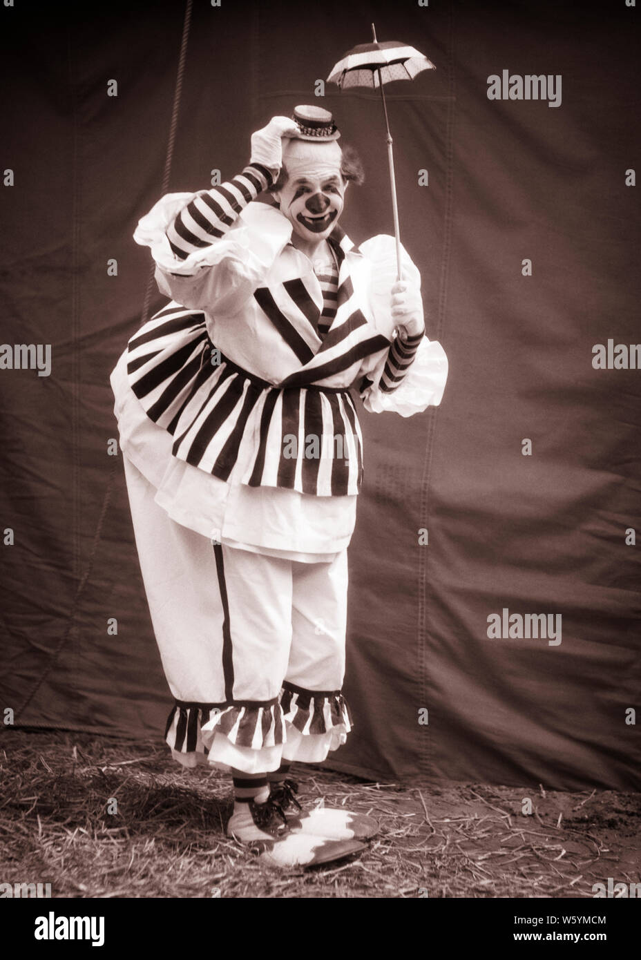 1930 BIG CLOWN SOUS SON PETIT PARAPLUIE TINY TIPPING HAT LOOKING AT CAMERA portant des chaussures de clown costume rayé OVERSTUFFED - c2690 HAR001 CARRIÈRE HARS JOIE COMIQUE ACTEUR DE VIE EMPLOI RAYÉ DE L'HISTOIRE DE L'ESPACE DE COPIE DES PERSONNES DE SEXE MASCULIN PROFESSION ENTERTAINMENT B&W CLOWNS CONTACT D'OEIL HUMORISTIQUE DE COMPÉTENCES COMPÉTENCES BONHEUR OCCUPATION SON INTERPRÈTE PARASOL CARRIÈRES composent l'artiste comique COMÉDIE ACTEURS MÉTIERS JESTER PETIT SPECTACLE DE LA CRÉATIVITÉ DES ARTISTES OVERSTUFFED TIPPING NOIR ET BLANC FOU HAR001 old fashioned Banque D'Images