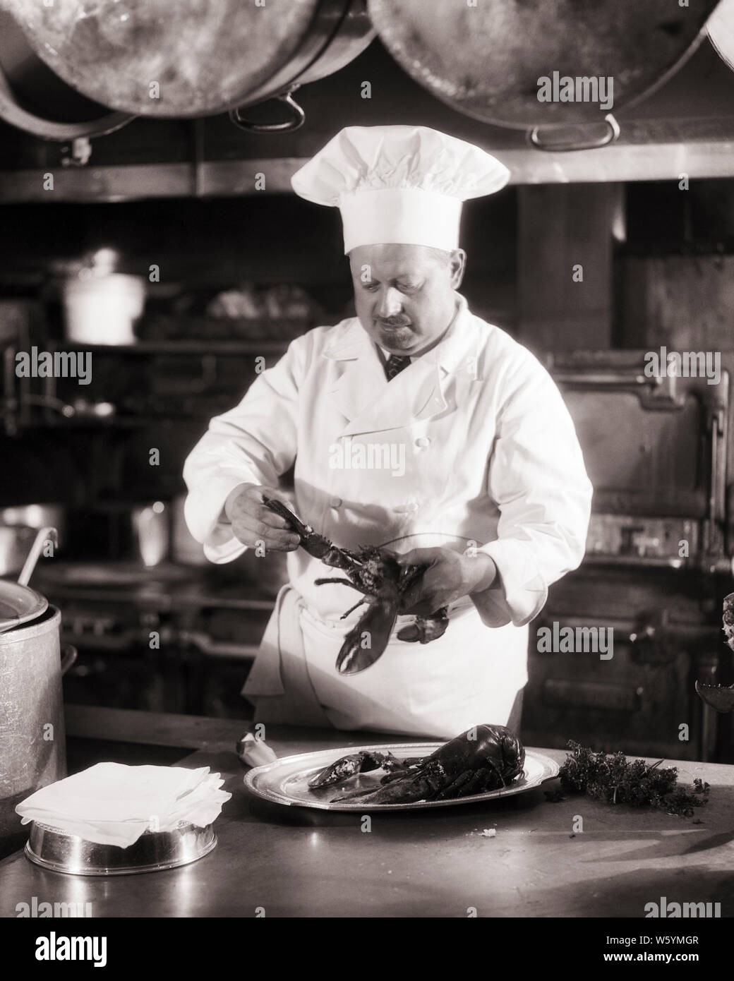 Années 1920 Années 1930 CHEF HOMME PORTANT TOQUE CUISINE PROFESSIONNELLE EN SE CONCENTRANT SUR LA PRÉPARATION D'un plat de homard - c3672 HAR001 H.A.R.S. B&W HOMME D'ÂGE MOYEN DE COMPÉTENCES COMPÉTENCES PROFESSION SUCCÈS MOUSTACHE MOUSTACHES SERVICE CLIENT CARRIÈRES CONNAISSANCES CHOIX FIERTÉ À L'AUTORITÉ SUR LES CHEVEUX DU VISAGE ÉLÉGANT CRÉATIVITÉ CONCEPTUELLE PROFESSIONS TOQUE NOIR ET BLANC DE L'ORIGINE ETHNIQUE CAUCASIENNE CONCENTRANT HAR001 old fashioned Banque D'Images