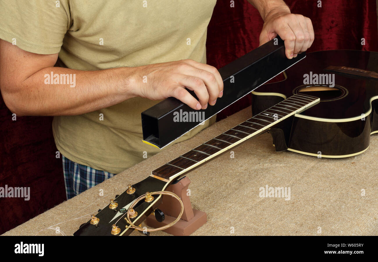 Réparation guitare instrument de musique et de service - Travailleur moud manche de guitare noire frettes. Banque D'Images