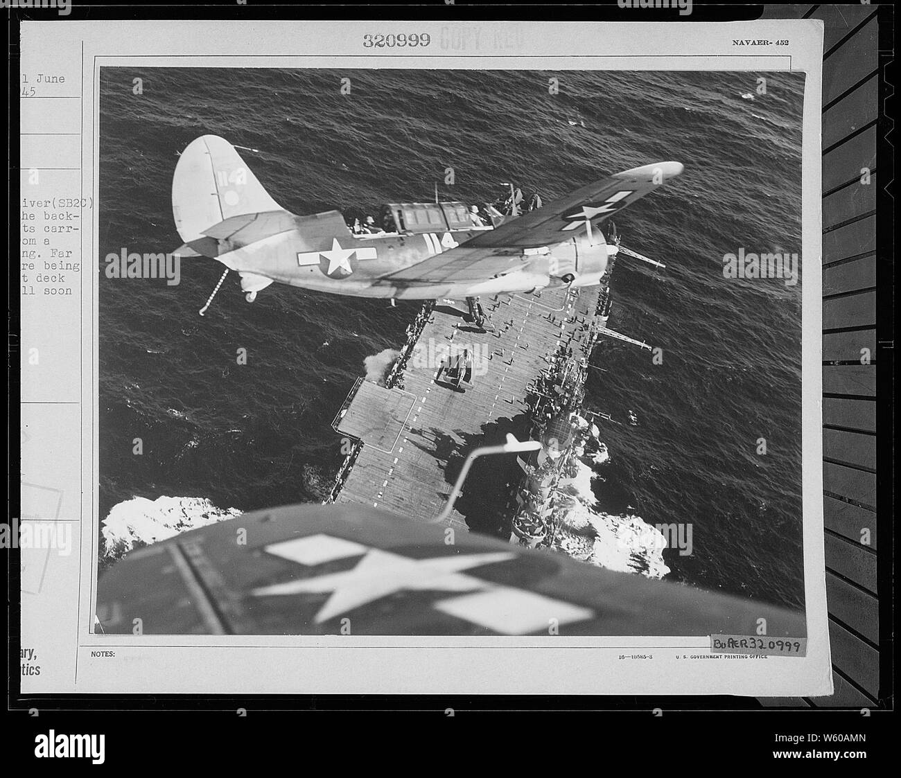 Un Curtiss Helldiver Marine (SB2C) est correctement positionné dans le contexte fourni par son opérateur, car il revient d'une grève à la Jap voyage. Bien au-dessous d'autres avions sont d'être repéré sur le pont pour que le SB2C sera bientôt de retour. Banque D'Images