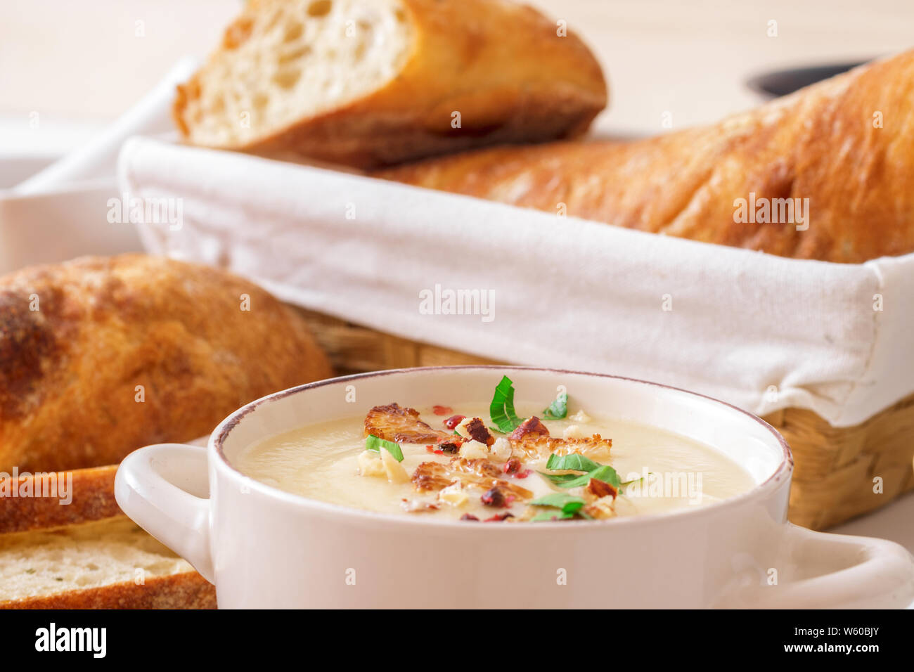 Table en bois blanc avec 2 bols de soupe au chou-fleur orné de noisettes concassées, poivron rouge, persil lisse les herbes, pain, friture torsadée Suisse Banque D'Images Table en bois blanc avec 2 bols de soupe au chou-fleur orné de noisettes concassées, poivron rouge, persil lisse les herbes, pain, friture torsadée Suisse Banque D'Images