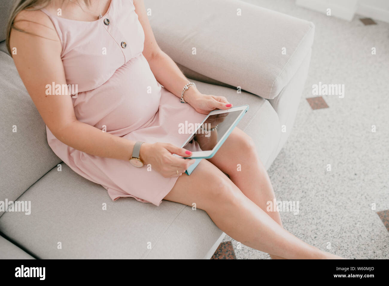 Pregnant woman sitting avec une tablette dans ses mains Banque D'Images