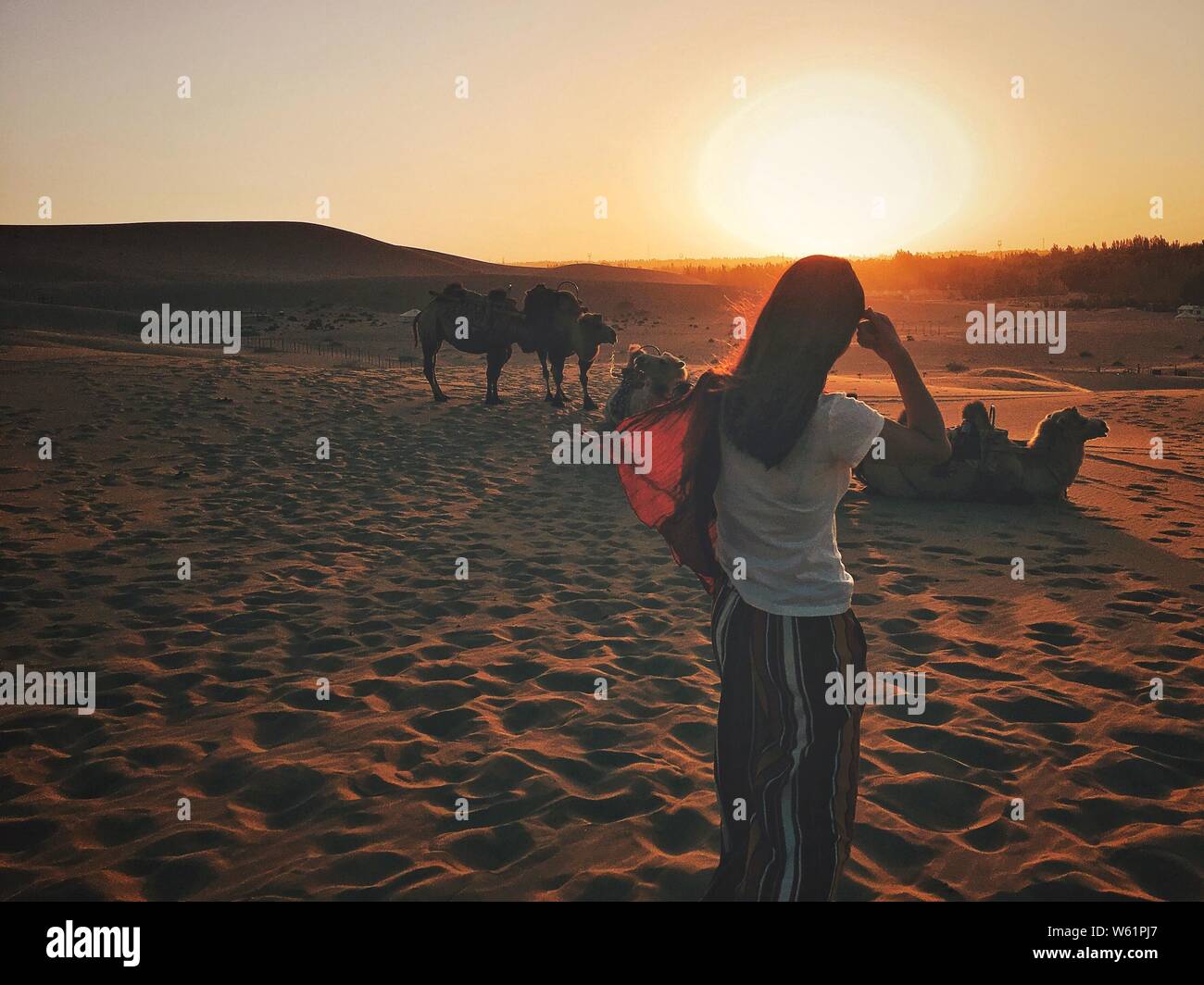 Un touriste pose pour des photos dans le désert de Gobi dans le Croissant de lune (Yueyaquan) et le chant des montagnes de sable dans endroit pittoresque, au nord de la ville de Dunhuang Banque D'Images