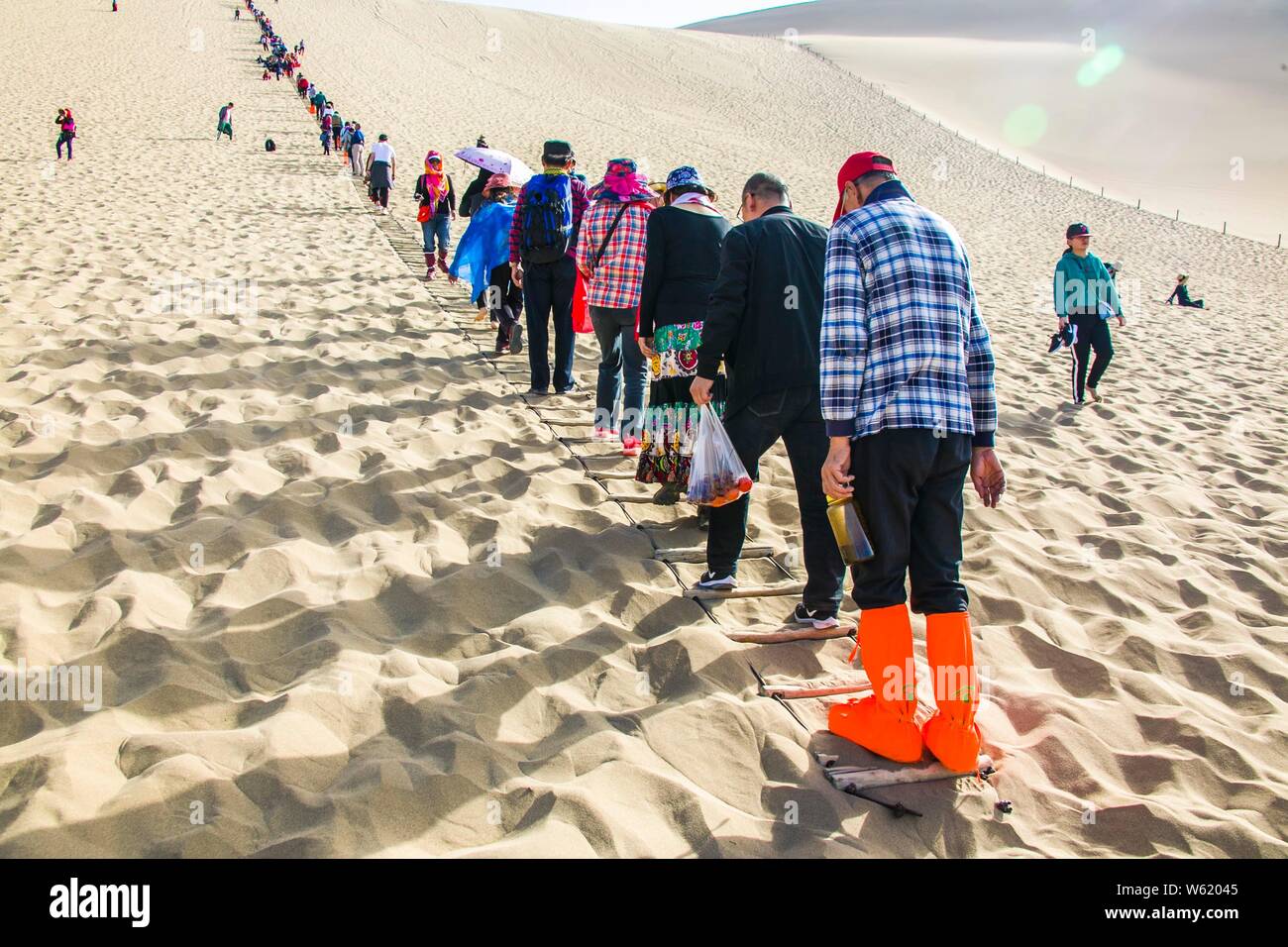 Les touristes à pied dans le désert de Gobi dans le Croissant de lune (Yueyaquan) et le chant des montagnes de sable dans endroit pittoresque ville de Dunhuang, dans le nord-ouest de la Chine. Banque D'Images