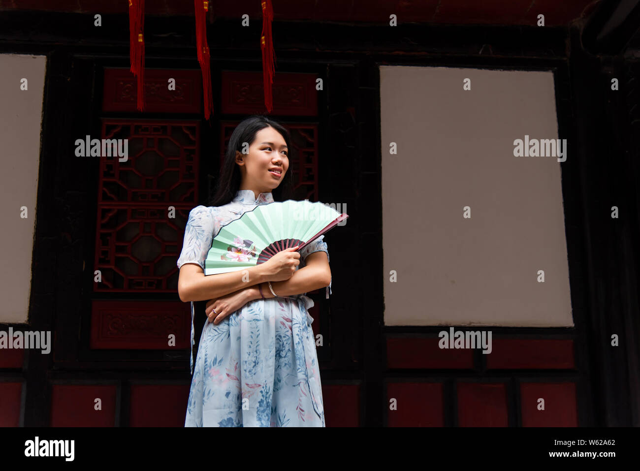 Femme Asiatique dans un temple tenant un portrait de ventilateur à main Banque D'Images