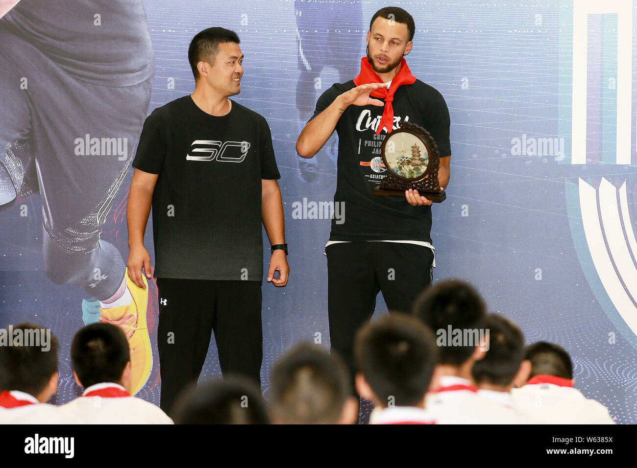 Star de la NBA Stephen Curry, droit, de Golden State Warriors parle lors de sa visite à l'école primaire rattachée à l'Université Huazhong des sciences et techn Banque D'Images