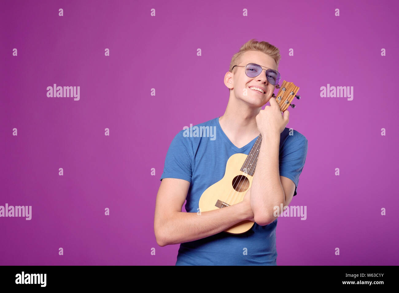 Man hugging guitar ukulele sur fond violet Banque D'Images