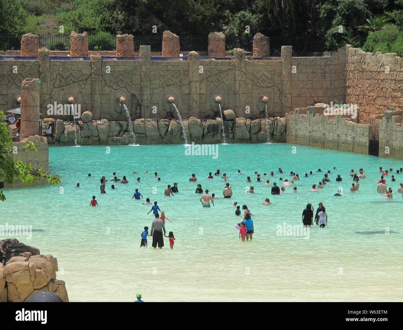 Foule de gens ou les nageurs debout dans l'eau bleu turquoise dans une piscine à vagues sur une chaude journée d'été à vallée des vagues à Sun City, Afrique du Sud Banque D'Images