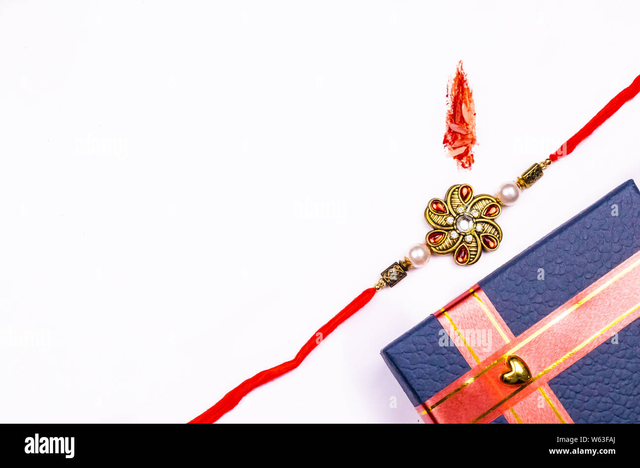 Raksha Bandhan concept - une boîte cadeau bleu avec Rakhi kumkum et marque de grains de riz sur un fond blanc Banque D'Images