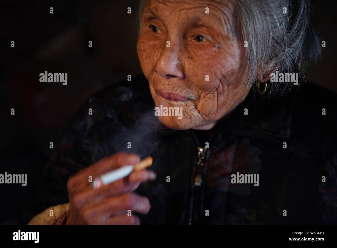 --FILE--une vieille femme chinoise fume à la comté Huoshan, Lu'an, ville de la Chine de l'est la province de l'Anhui, 18 février 2018. Les ventes de tabac de la Chine r Banque D'Images