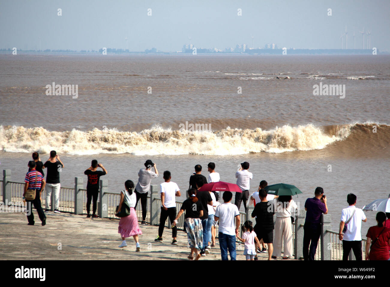 Les visiteurs et les résidents watch ondes d'un mascaret de rivière Qiantang jaillissant sur la rive du fleuve à Haining City, Zhejiang en Chine est de bauvin Banque D'Images