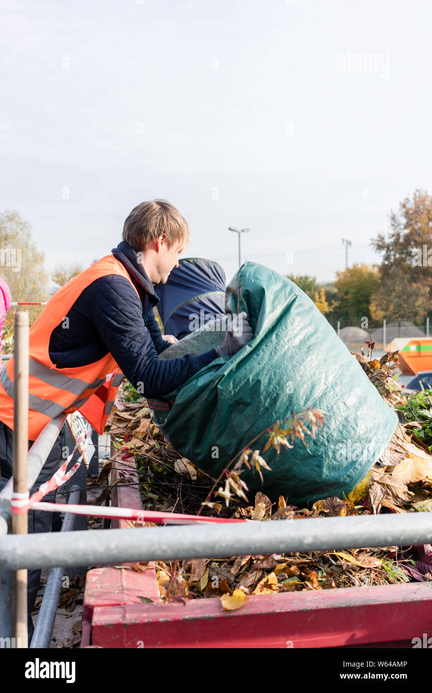 L'homme en vert déchets donnant sur le centre de recyclage de contenants Banque D'Images