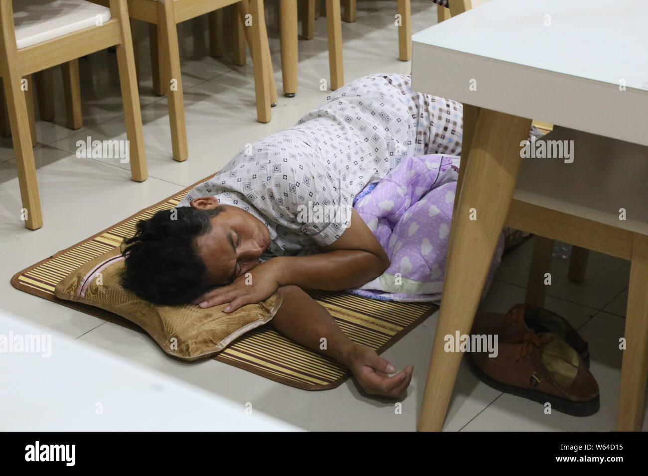 Un parent d'un étudiant de première année, qui conduit son enfant à l'inscription lors de sa première journée d'étude, dort sur le plancher à une cantine dans une université en Z Banque D'Images